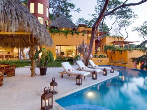 Villa Mandarinas: This color-drenched villa just 15 minutes from quaint downtown is located on the oceanfront side of the small community of Mismaloya, facing renowned Los Arcos National Park. 	Enter via the Palapa reception area which also leads to a fitness center with elliptical trainer, treadmill, hand weights, workout bench, exercise mats and an amazing view of the beach. The next level boasts three master bedrooms, each with king bed, walk-in closet, en suite bath with jacuzzi, and lare oceanfront terrace. 	The main level provides a well-appointed living room and en suite family room with 50